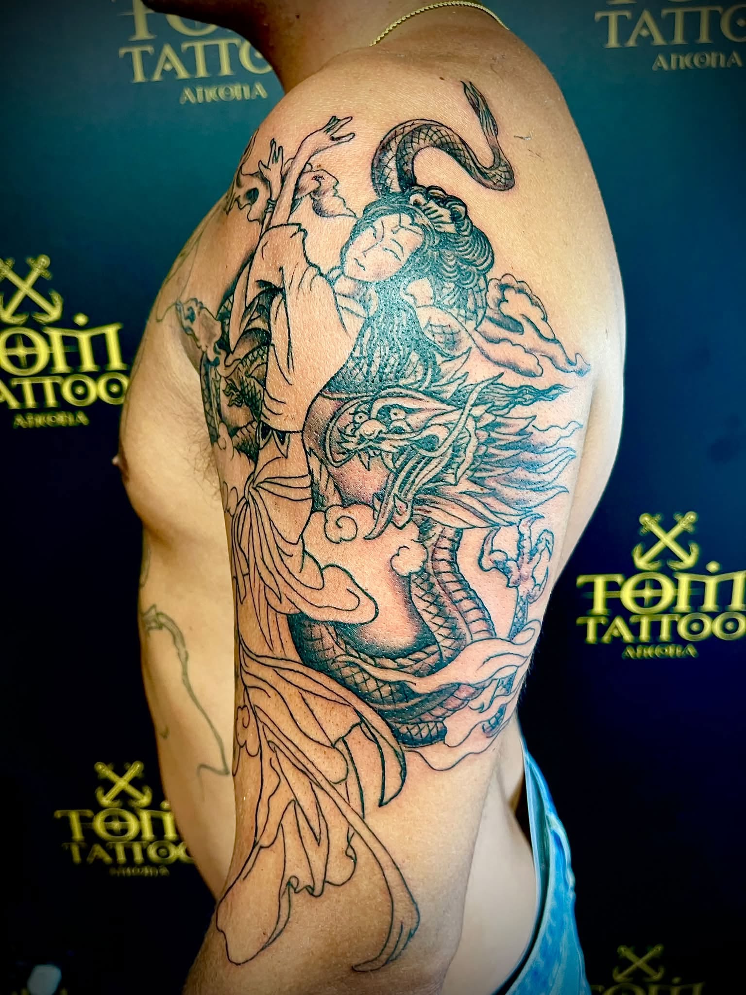 Tatuaggio in stile giapponese con drago e geisha su braccio, realizzato ad Ancona